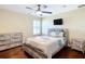 Neutral bedroom with hardwood floors, a ceiling fan, and large window with shutter shades at 7688 Se 135Th St, Summerfield, FL 34491