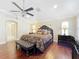 Bright main bedroom boasts hardwood floors, a ceiling fan, and a seating bench at the foot of the bed at 7688 Se 135Th St, Summerfield, FL 34491