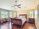 Cozy main bedroom with hardwood floors, a ceiling fan, and natural light from large windows at 7688 Se 135Th St, Summerfield, FL 34491