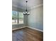 Inviting dining room showcasing wood floors, decorative chandelier, and natural light from the large window at 8481 Sw 137 Ct, Dunnellon, FL 34432