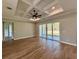 Bright living room featuring wood floors, a tray ceiling with fan, and sliding glass doors to the outdoors at 8481 Sw 137 Ct, Dunnellon, FL 34432