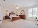 Spacious main bedroom featuring wooden furniture, a ceiling fan, and a large window overlooking the neighborhood at 8510 Sw 108Th Place Rd, Ocala, FL 34481