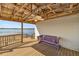 Covered waterfront deck with wooden floors, ceiling fan, and purple bench overlooking the lake at 10900 Se Timucuan Rd, Summerfield, FL 34491