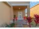 Covered front porch features neutral tones, two red chairs, and green landscaping at 12312 Ne 48Th Loop, Oxford, FL 34484