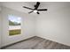 Well-lit bedroom with gray floors, ceiling fan, and a large, light-filled window at 13743 Sw 113 Ln, Dunnellon, FL 34432