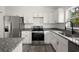 A modern kitchen with granite counters, stainless appliances, white cabinets, and wood-look flooring at 13743 Sw 113 Ln, Dunnellon, FL 34432