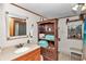 Bathroom features a wooden shelf, sink, mirror, and neutral walls with light tile floor at 19390 Se 95Th Pl, Ocklawaha, FL 32179