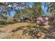 A serene exterior view featuring a home and outbuildings, framed by majestic trees and a clear blue sky at 19390 Se 95Th Pl, Ocklawaha, FL 32179