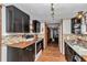 Open kitchen with black cabinets, mosaic backsplash, wood-look floor, and view into dining room at 19390 Se 95Th Pl, Ocklawaha, FL 32179