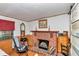 Comfortable room with brick fireplace, rocking chair, wood paneled walls, and wood floors at 19390 Se 95Th Pl, Ocklawaha, FL 32179