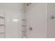 This shower features white walls and fixtures, a multi-setting shower head, built-in shelves, and chrome knobs at 24264 Sw South Hills Ct, Dunnellon, FL 34431