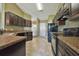 A kitchen featuring dark wood cabinetry, sleek black appliances and tan countertops and tile floors at 38 Juniper Loop Way, Ocala, FL 34472