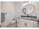 Stylish half-bathroom with granite countertop, round mirror, white cabinets and new fixtures at 4940 E Fort King St, Ocala, FL 34470
