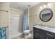 Bathroom featuring a shower with shelving, toilet, and vanity with dark wood cabinet and round mirror at 4940 E Fort King St, Ocala, FL 34470