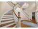 Elegant foyer featuring a curved staircase, hardwood floors, and a stunning chandelier, creating a welcoming atmosphere at 4940 E Fort King St, Ocala, FL 34470