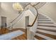 Elegant foyer featuring a curved staircase, hardwood floors, and a stunning chandelier, creating a welcoming atmosphere at 4940 E Fort King St, Ocala, FL 34470