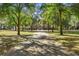 Long driveway leading up to beautiful brick house surrounded by mature trees at 4940 E Fort King St, Ocala, FL 34470