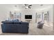 Spacious living room featuring a large navy sofa, two windows with curtains, and a ceiling fan at 4940 E Fort King St, Ocala, FL 34470