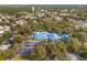 An aerial shot shows a community pool and buildings with blue roofs amidst a lush, tree-filled neighborhood at 10824 Sw 90Th Ter, Ocala, FL 34481