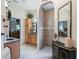 Bathroom featuring tile flooring, granite countertops, wooden cabinets, and a glass shower with an arched entryway at 11084 Se 168Th Loop, Summerfield, FL 34491