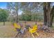 Relaxing backyard setting with a stone fire pit, surrounded by colorful chairs and mature trees at 11725 79Th Cir, Ocala, FL 34476