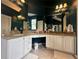 Bathroom with granite counters, white cabinets, double sinks, and ample lighting at 130 Harbour Cove Way, Clermont, FL 34711