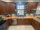 Well-lit kitchen featuring wood cabinets, granite countertops, stainless steel appliances, and backyard window at 130 Harbour Cove Way, Clermont, FL 34711