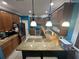 Bright kitchen featuring wood cabinets, granite countertops, stainless steel appliances, and modern pendant lighting at 130 Harbour Cove Way, Clermont, FL 34711
