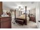 Comfortable main bedroom featuring a four-poster bed, carpet flooring, and natural lighting at 13057 Sw 85Th Cir, Ocala, FL 34473