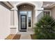 Close up of home entrance showing decorative glass in front door and manicured landscaping and neutral stucco facade at 13187 Se 93Rd Terrace Rd, Summerfield, FL 34491