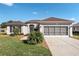 Well-kept single-story house featuring a two-car garage, tidy landscaping, a walkway to the front door, and a green lawn at 13187 Se 93Rd Terrace Rd, Summerfield, FL 34491