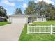 Inviting single-Gathering home with a well manicured lawn, a white picket fence, and an attached garage at 14605 Sw 20Th Pl, Ocala, FL 34481