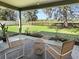 A shaded patio with two wicker chairs overlooks a lush, expansive backyard at 14605 Sw 20Th Pl, Ocala, FL 34481