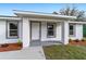 A close-up view of the covered front porch with gray trimmed windows and landscaping at 15123 Se 63Rd Ct, Summerfield, FL 34491