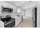 An open-concept kitchen with stainless steel appliances, white cabinets, and gray counter tops at 15123 Se 63Rd Ct, Summerfield, FL 34491