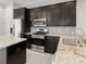 Close-up of a modern kitchen featuring dark cabinetry, stainless steel appliances, and granite countertops at 2032 Se 27Th Rd, Ocala, FL 34471