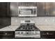 Detailed kitchen view with a stainless steel microwave and stove set against a mosaic tile backsplash at 2032 Se 27Th Rd, Ocala, FL 34471