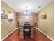 Traditional dining room with cherry tone wood floors, wood accent wall and view into kitchen at 3437 E Fort King St # 220, Ocala, FL 34470