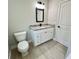 Bright bathroom featuring a white vanity with granite countertop, modern mirror, and commode at 3684 Se 130Th Pl, Belleview, FL 34420