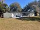 Back exterior view featuring neutral siding, a spacious backyard, and detached garage at 4480 Ne 25Th Ave, Ocala, FL 34479