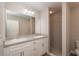 Bathroom featuring double sinks with white cabinets, a large mirror, and a tiled walk-in shower at 46 Malauka Dr, Ocklawaha, FL 32179