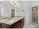 Elegant bathroom featuring a double sink vanity, decorative lighting, and a tiled shower stall at 4620 Nw 84Th Ter, Ocala, FL 34482