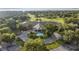 Beautiful aerial view of a sprawling clubhouse with a circular driveway and fountain, surrounded by lush landscaping and a golf course at 6174 Spinnaker Loop, Lady Lake, FL 32159