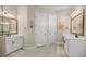 Dual sink bathroom boasts white vanities, framed mirrors, and neutral color palette at 6174 Spinnaker Loop, Lady Lake, FL 32159