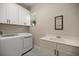 The laundry room features white cabinets, a utility sink and a front load washer and dryer at 6174 Spinnaker Loop, Lady Lake, FL 32159