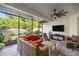 The screened-in patio includes an orange sofa set, ceiling fan, and television at 6174 Spinnaker Loop, Lady Lake, FL 32159