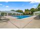 A swimming pool surrounded by lounge chairs and palm trees, and a white clubhouse with covered patio under a sunny sky at 7451 Sw 111Th Pl, Ocala, FL 34476