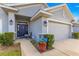 Close up of front entrance with blue potted flowers, stone accents, and a gray stucco facade at 1 Diamond Cove Pl, Ocala, FL 34472