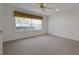 Bright bedroom featuring a ceiling fan, neutral carpet, and large window, offering ample natural light at 10003 Sw 90Th Loop, Ocala, FL 34481