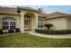 Inviting front entrance featuring an arched doorway, manicured landscaping, and well-maintained lawn at 10884 Sw 53Rd Cir, Ocala, FL 34476